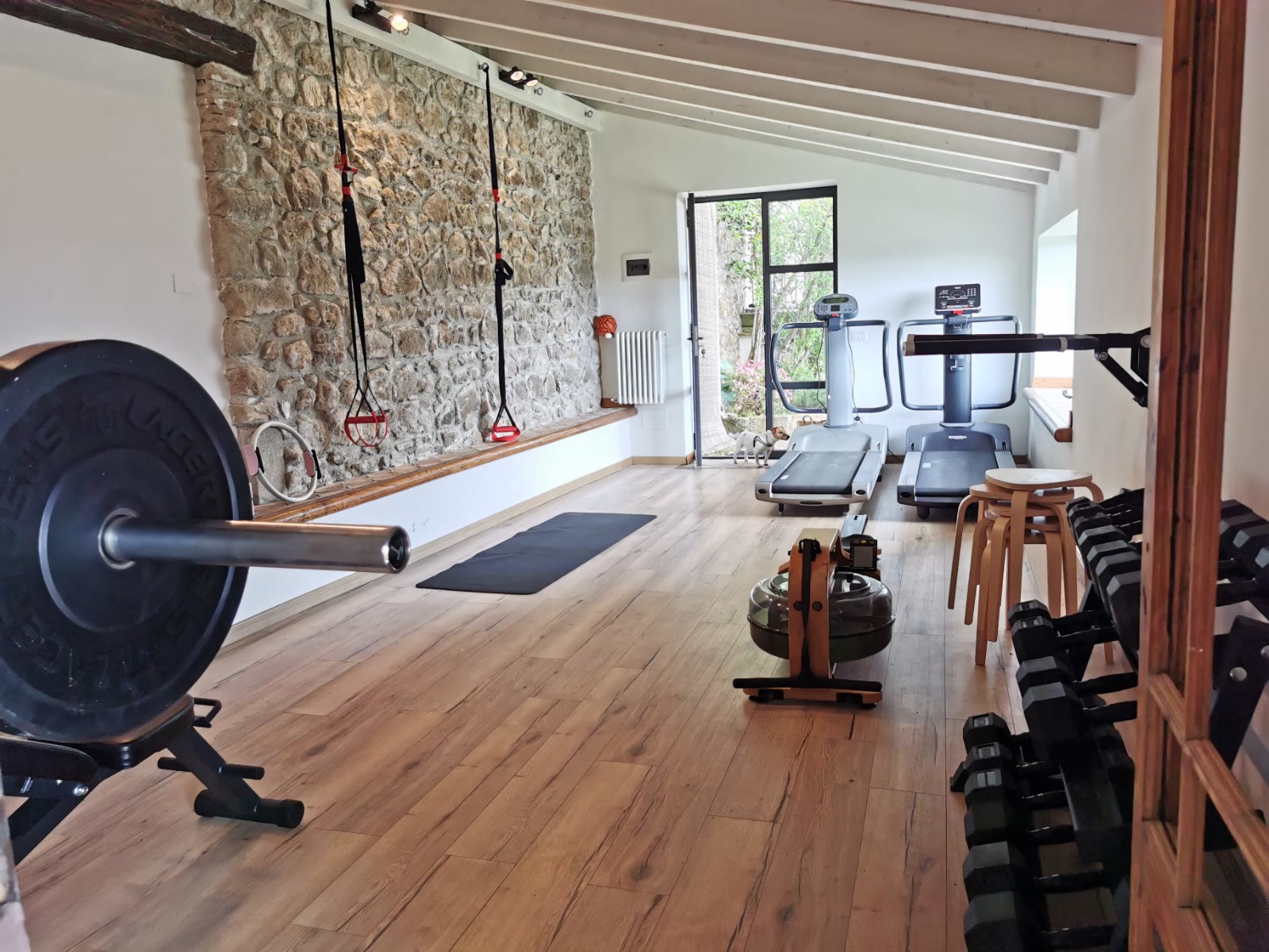 The renovated private gym with stone wall, rack, rower and treadmill
